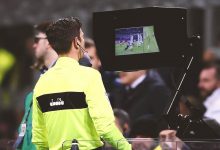 An arbitrator using a Video Assitant Referee (VAR) during a match